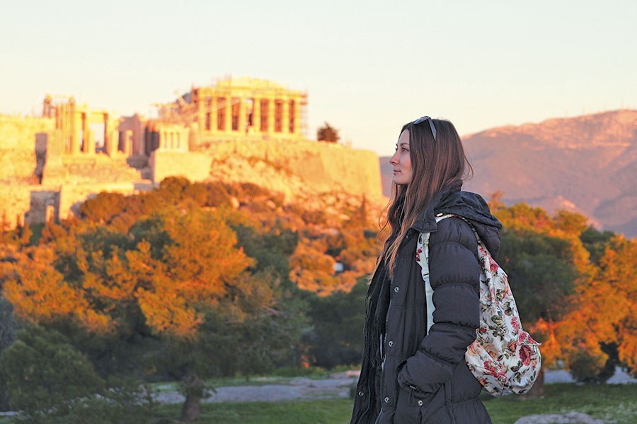 student with backpack walking by the Parthenon