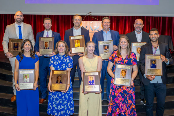 10 alumni athlete honorees hold their new plaques with photos of them as athletes