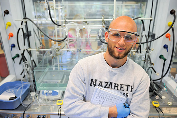 student standing in front of laboratory equipment