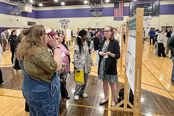 student presenting poster to onlookers