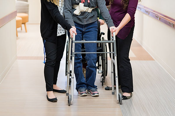 physical therapists assisting client with a walker