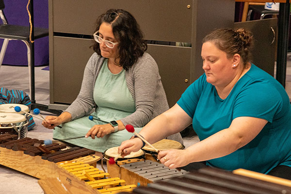 students sitting on floor playing xylophones