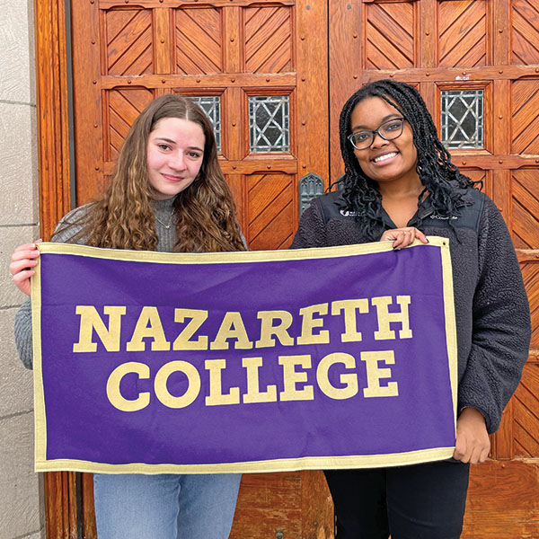 two students holding a banner that says "Nazareth College"