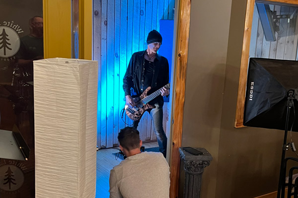 Nathan works in the foreground as a musician plays guitar in recording studio