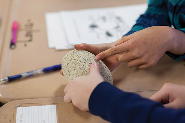 young child studying rock sample