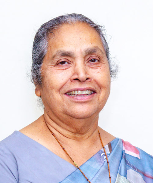 Lucy Kurien in an outfit with a blue-and-white patterned fabric draped over her shoulder. 