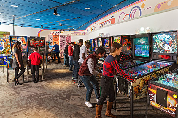 people playing pinball machines at Strong Museum of Play