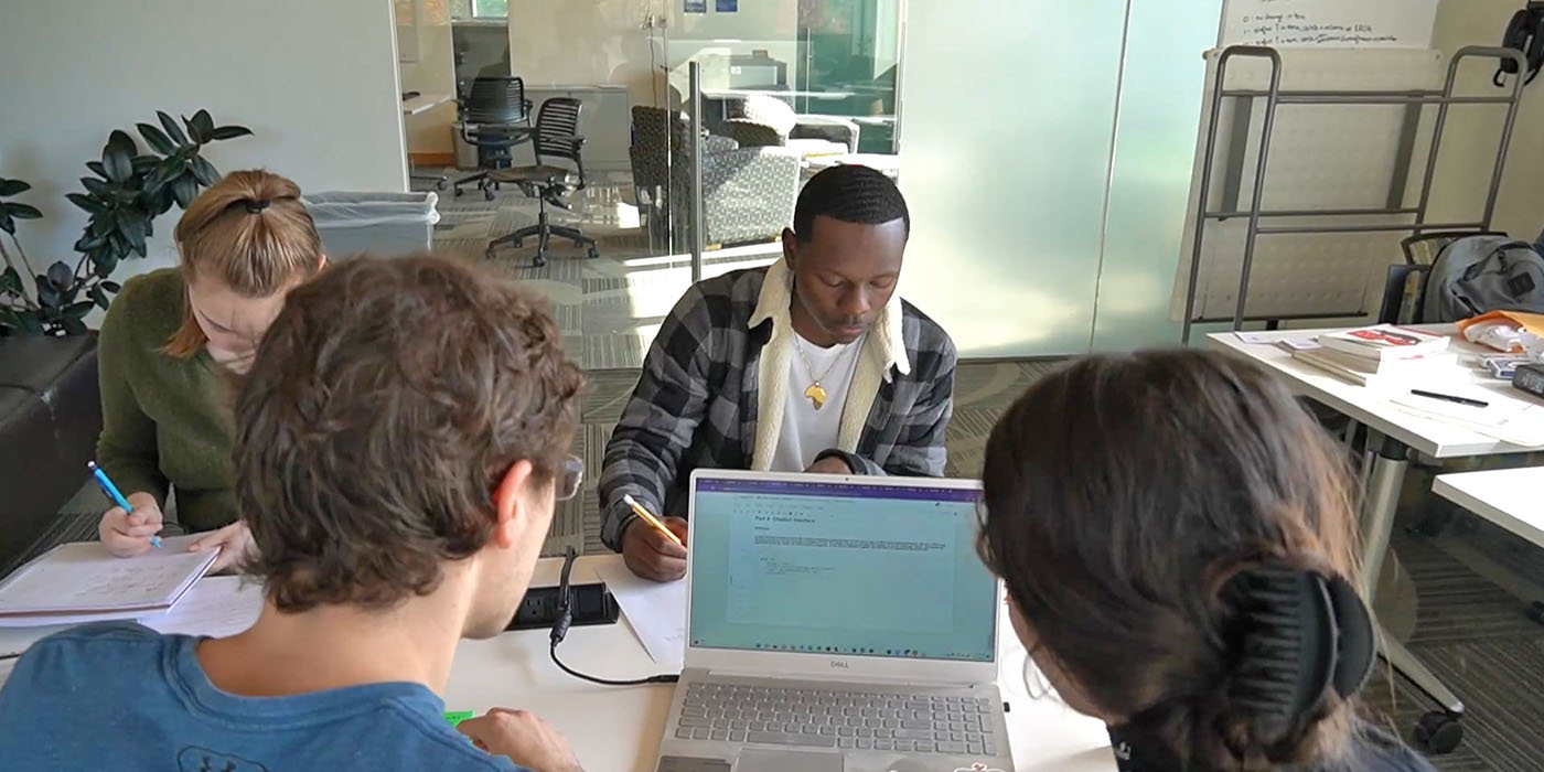 a group of people sitting around a table with a laptop