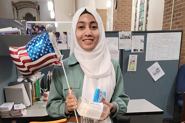 Ayat Al Sallami holds an American flag at her internship at Mary's Place