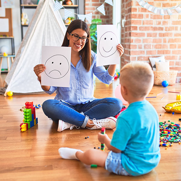 psychologist showing happy and sad faces to a young child