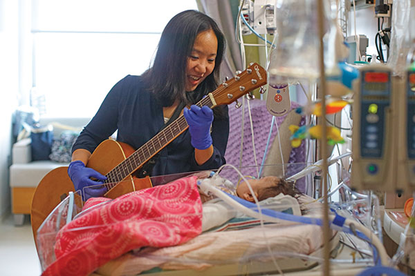 student playing guitar for child in hospital