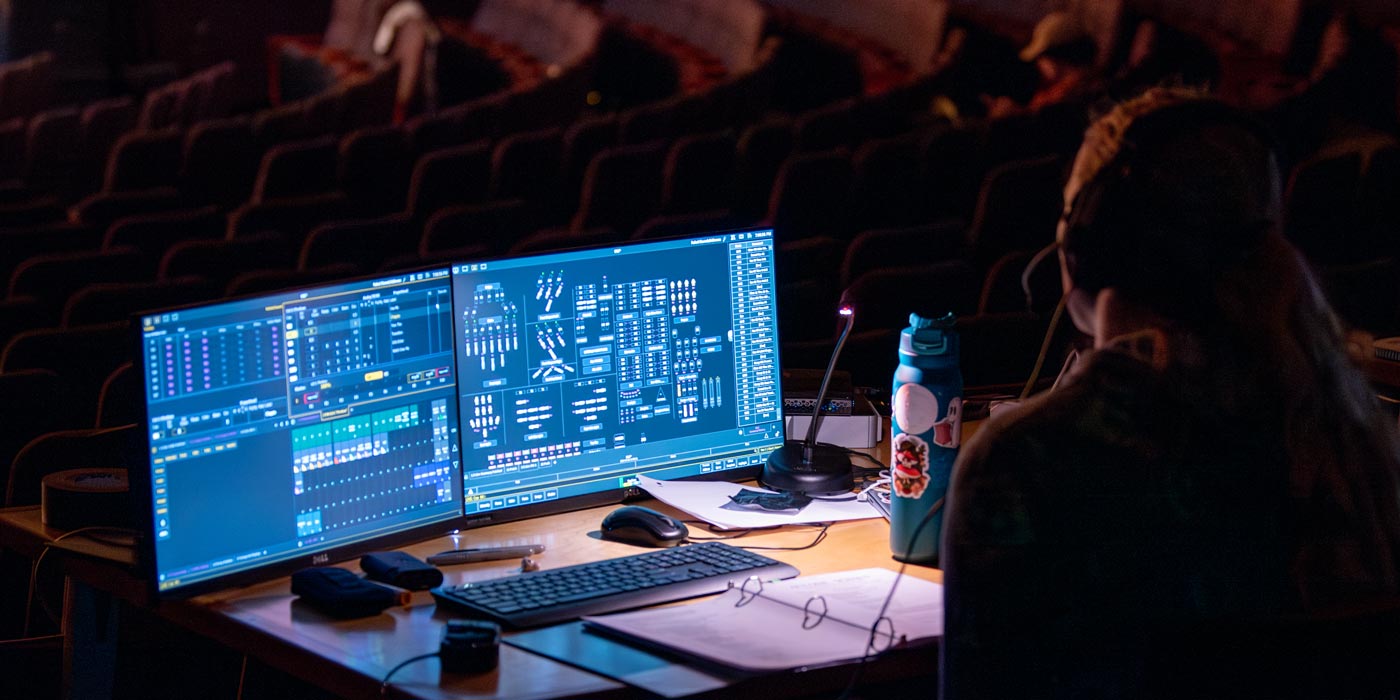 Naz student at theatre tech board in darkened theater