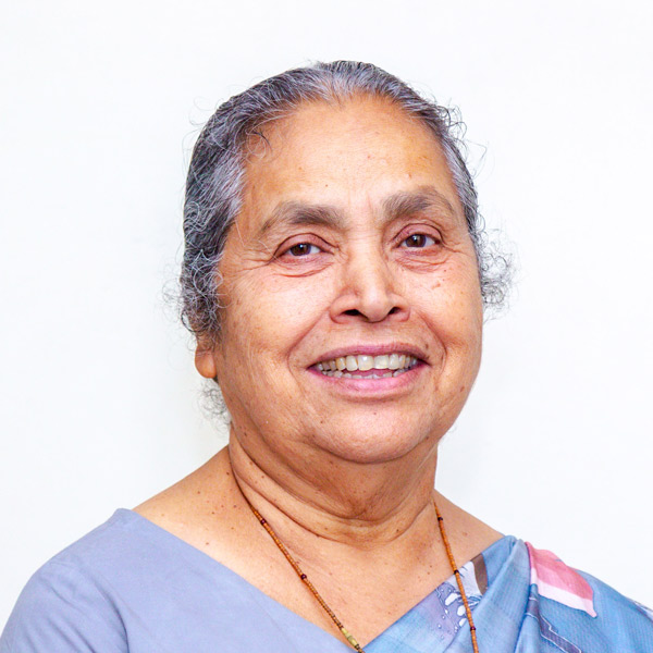 Lucy Kurien in an outfit with a blue-and-white patterned fabric draped over her shoulder. 